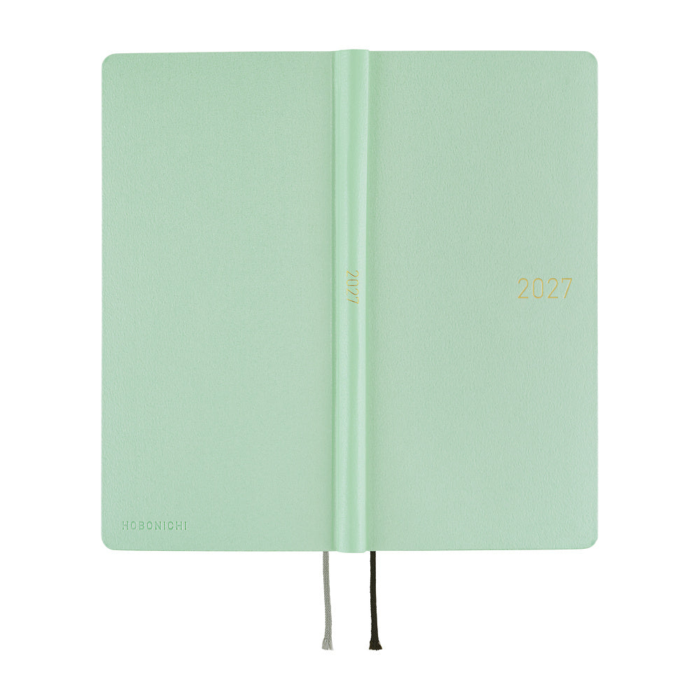 The exterior of a frosty green 2027 planner, shown closed with thin ribbon bookmarks hanging from the bottom edge, set against a plain white background.