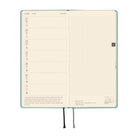 An open planner showing two interior pages: the left page has a weekly schedule layout for June 21st through 27st, and the right page has a grid.