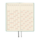 An open 2027 planner with a frosty green cover, showing a yearly calendar spread on cream pages.
