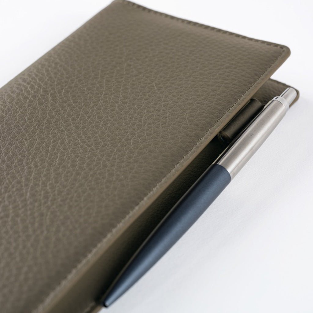 Front of warm gray leather Hobonichi Weeks cover with pen on white background