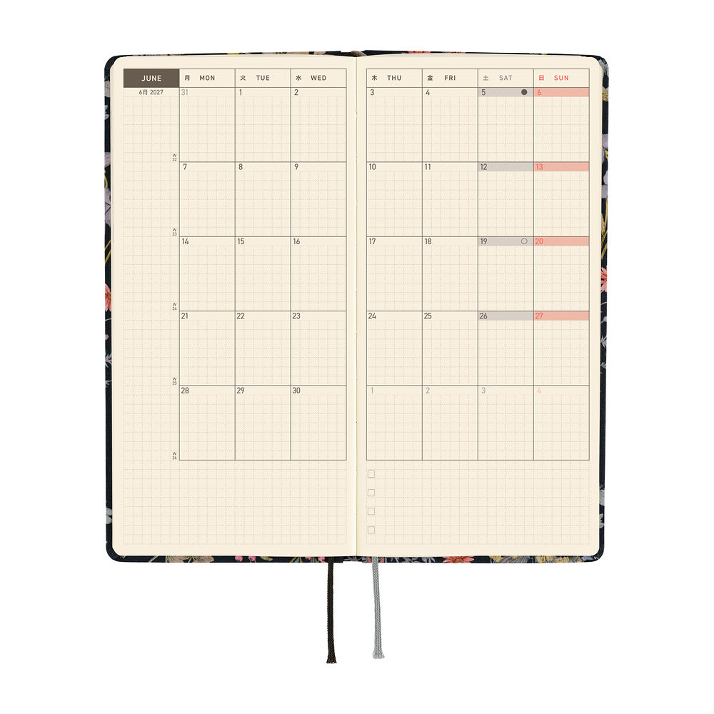 An open planner showing a monthly calendar spread on cream grid pages. 