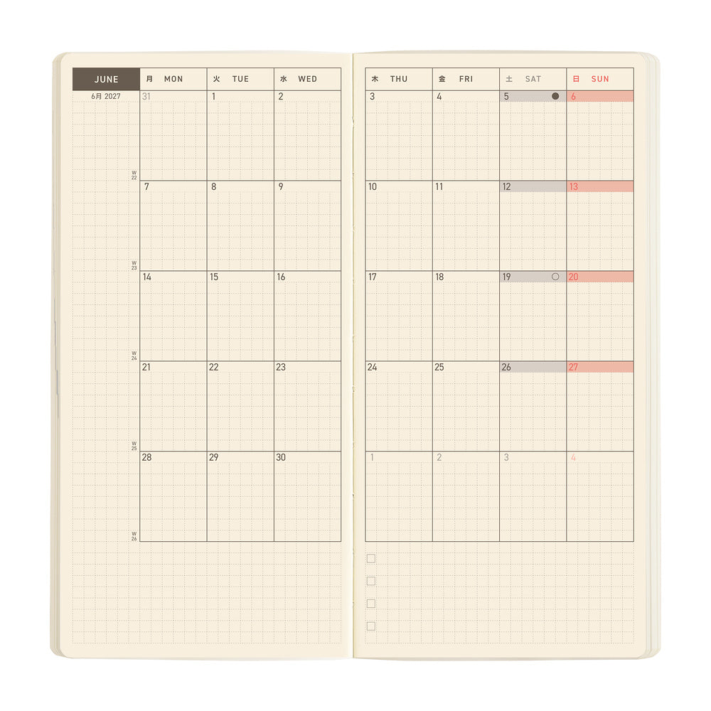 An open planner showing a monthly calendar spread on cream grid paper. 