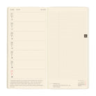 An open planner showing a weekly layout page on the left with dates from June 21 to 27, moon phase icons, and a short quote, alongside a large grid page on the right.