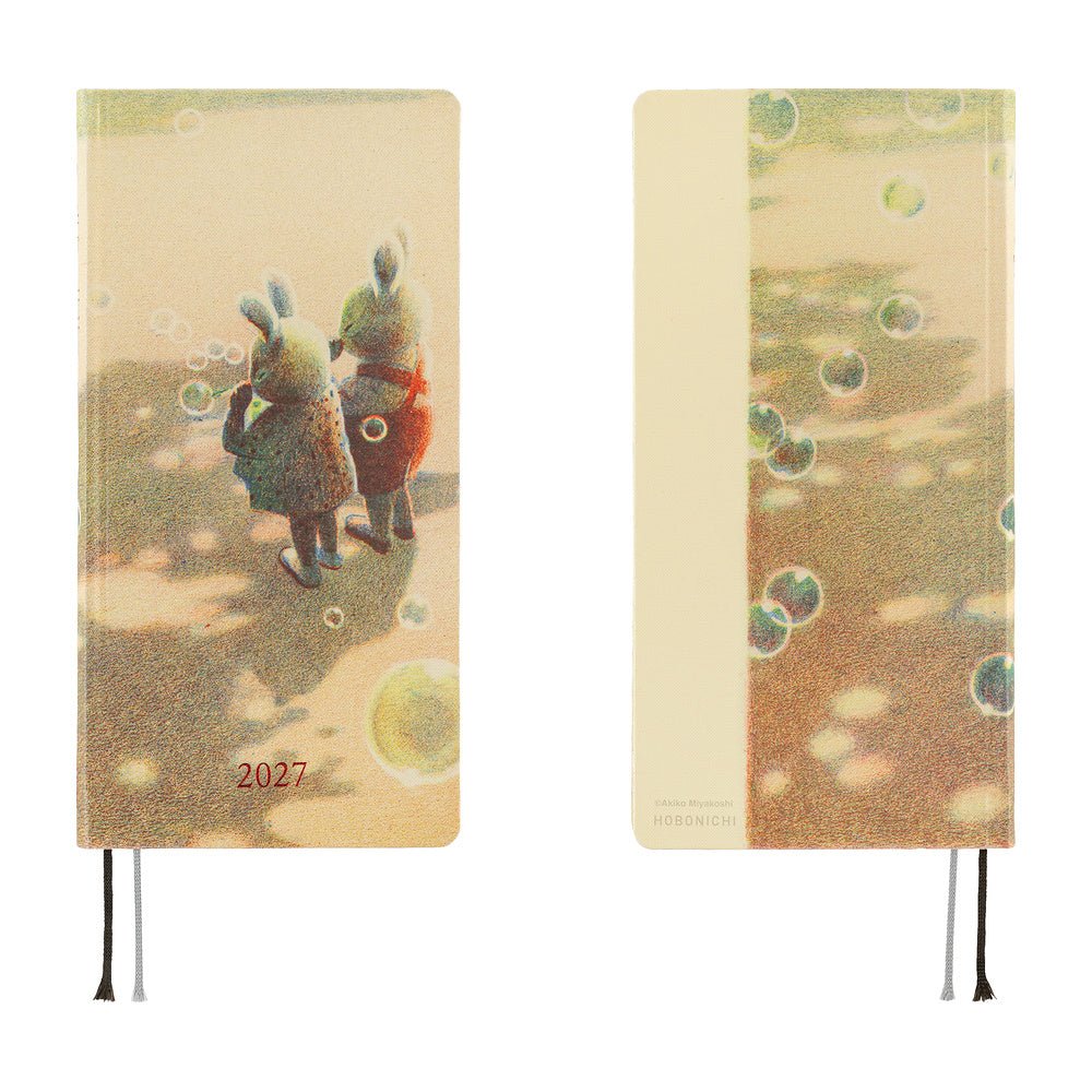 A front and back view of a 2027 planner. The front shows two rabbits blowing bubbles on a sandy-colored background. The back features bubbles floating over a shade-dappled surface. 