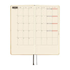 An open planner with a monthly calendar spread on cream grid paper, on a white background.