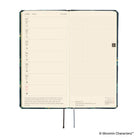 An open weekly planner spread on a white background. The left page shows a weekly schedule with small icons and a short quote at the bottom.