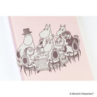 A close-up of a planner cover featuring illustrations showing Moomin characters gathered around a table. 