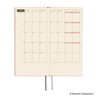 An open planner with a monthly calendar spread on cream grid pages, shown on a white background. 