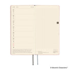 An open planner showing a weekly layout page with lined days on the left and a grid section on the right, photographed on a clean white background. 