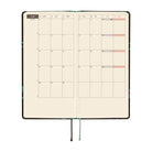 An open planner showing a two-page monthly calendar spread on cream grid pages.