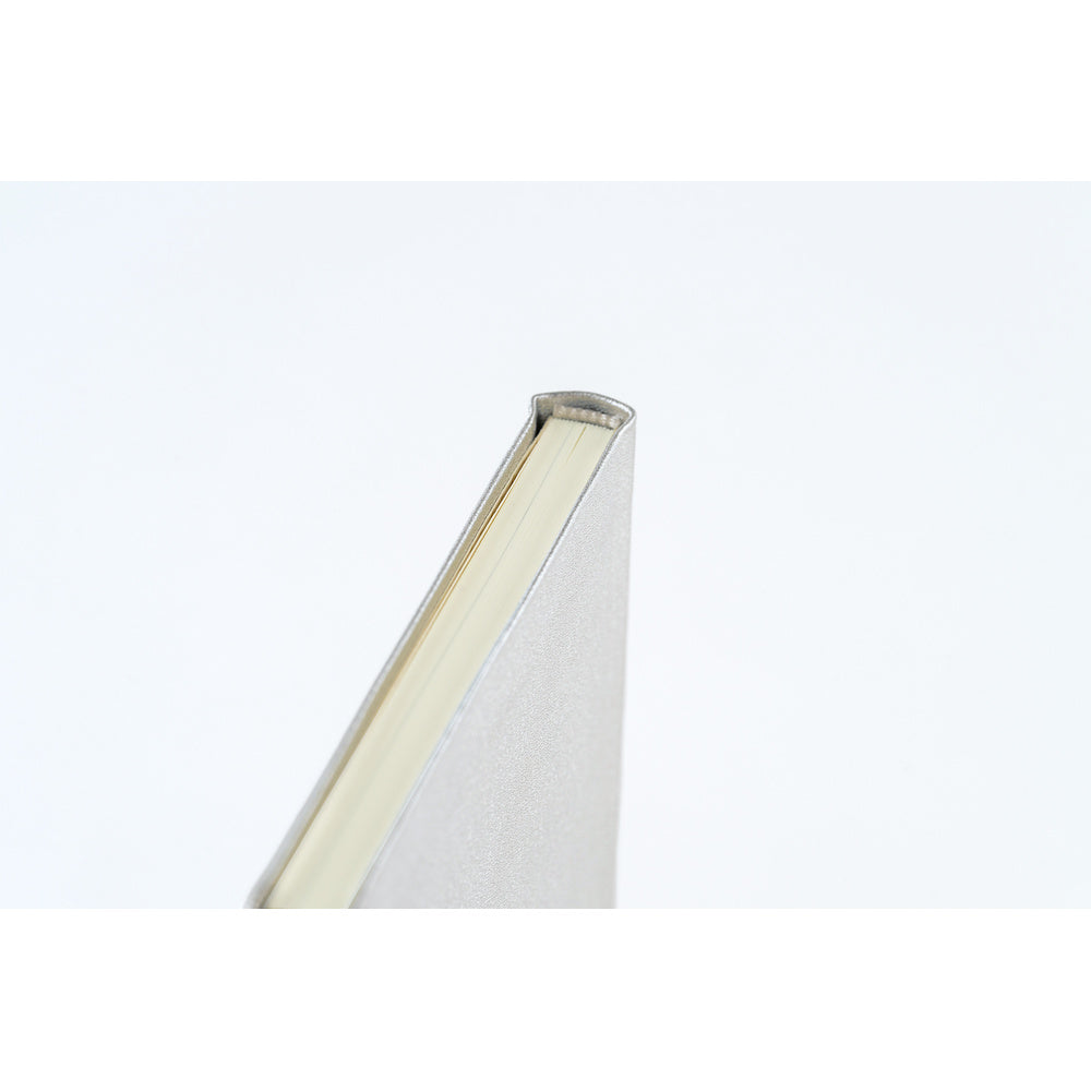 A close-up shot of the binding of a planner book with a silver leather cover and cream colored pages. 