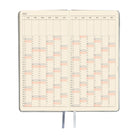 An open planner showing a yearly calendar spread with cream-colored pages and black grid lines.