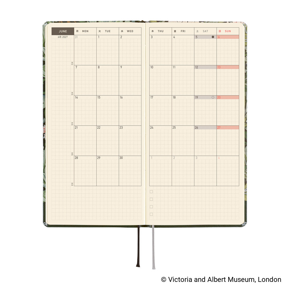 An open monthly calendar planner with cream grid pages, a floral-patterned cover visible along the edges, and a black ribbon bookmark. 