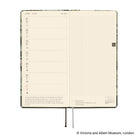 An open planner showing two interior pages: a weekly layout on the left with cream paper and a light grid page on the right. 