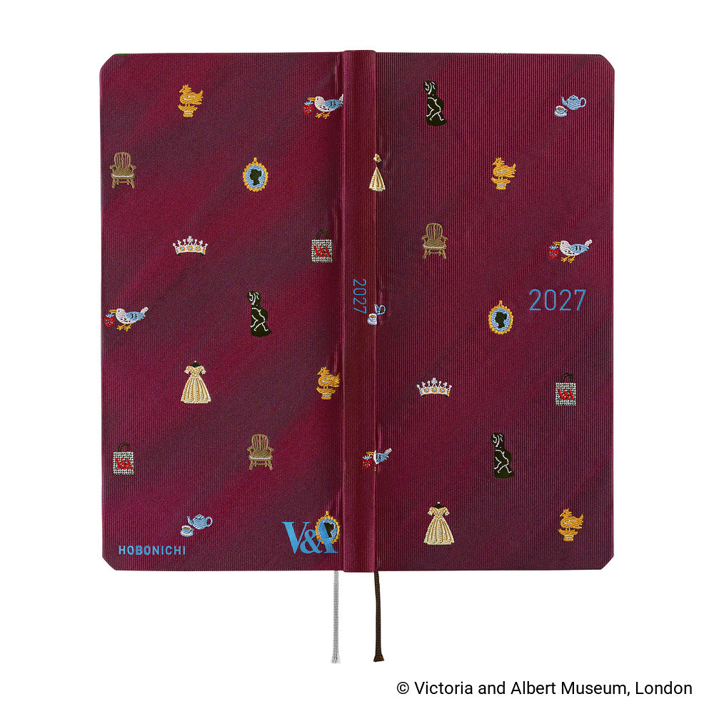 The exterior of a 2027 journal covered in woven "bow & tie" fabric featuring icons from the Victoria & Albert museum collection, such as a crown, teapot, chair, and dress. The back of the cover features the Hobonichi and V&A logos.