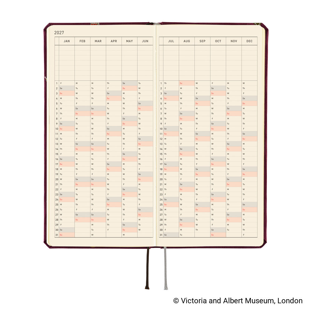 An open planner showing a 2027 yearly calendar spread, with cream pages. A ribbon bookmark hangs from the bottom.