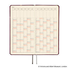 An open planner showing a 2027 yearly calendar spread, with cream pages. A ribbon bookmark hangs from the bottom.