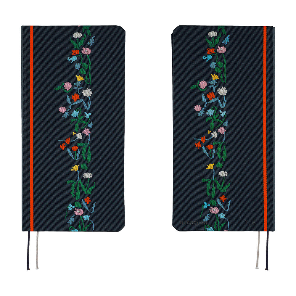 A front and back view of a dark navy blue planner with a vertical floral vine design in green, pink, blue, yellow, and white along the right side. It features a bright red band near the spine and ribbon bookmarks hanging from the bottom.
