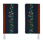 A front and back view of a dark navy blue planner with a vertical floral vine design in green, pink, blue, yellow, and white along the right side. It features a bright red band near the spine and ribbon bookmarks hanging from the bottom.
