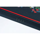 The spine of a navy blue planner, showing the year 2027. 