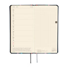 An open weekly planner spread with cream-colored pages. The left side features a Monday through Sunday layout, while the right side is an open grid. 