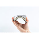 A hand holding a slim, flexible planner that curves gently under tension against a clean white background.
