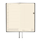 An open planner with cream-colored pages, showing a weekly layout on the left and a grid section on the right, photographed on a plain white background.