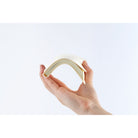 A hand holding a flexible, cream-colored planner that curves upward. 