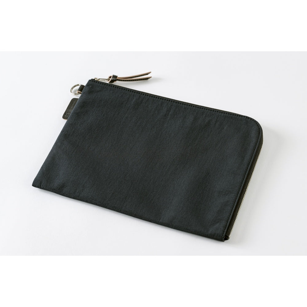 A black zippered pouch with a small leather tassel pull and a small fabric brand tag, photographed on a clean white background.