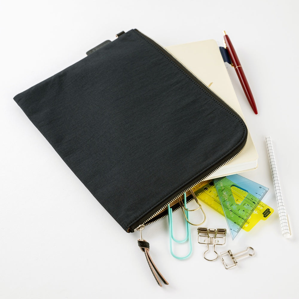 Black zippered pouch with stationery items on a white background