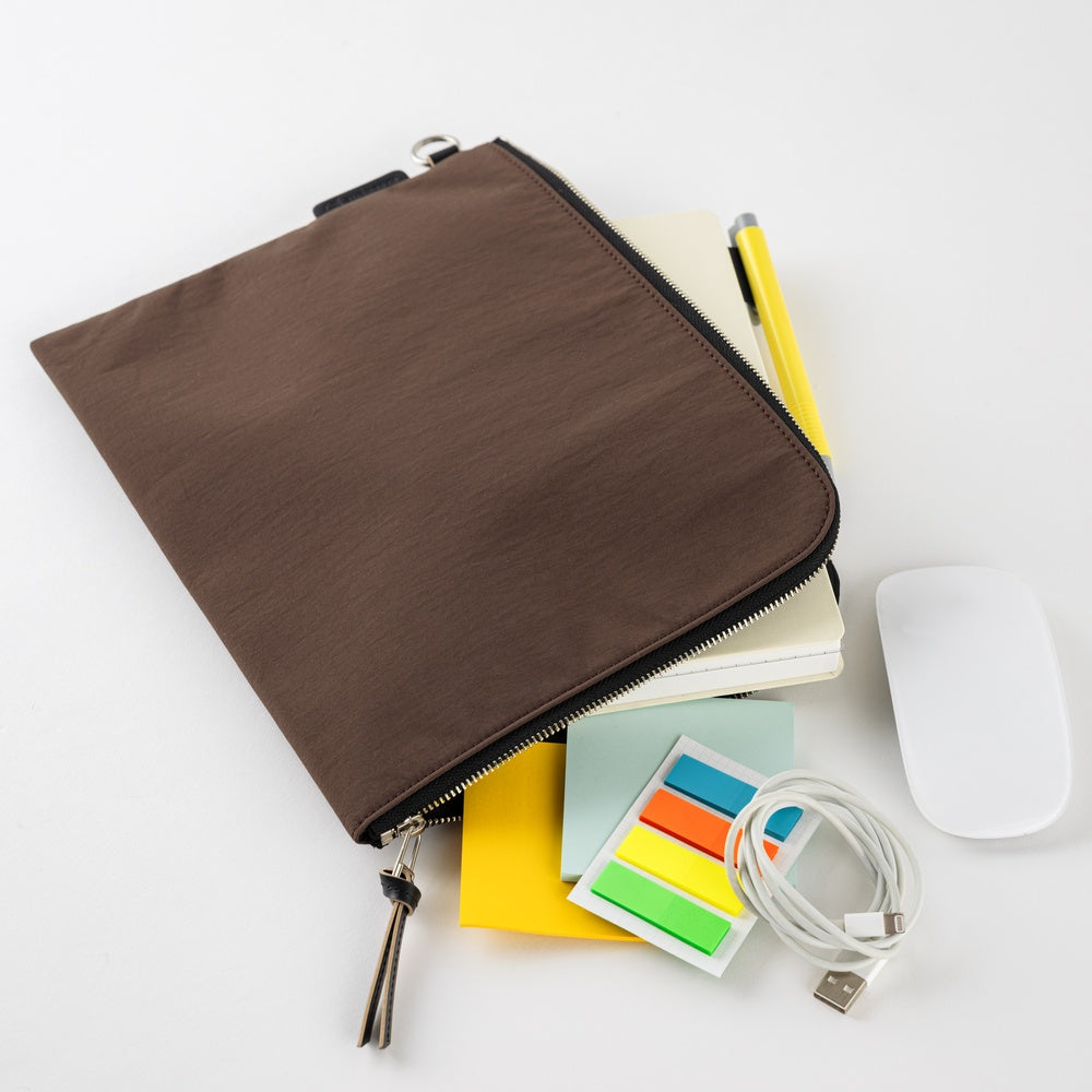 Brown zippered pouch with office supplies including a notebook, mouse, and colorful sticky notes on a white background.
