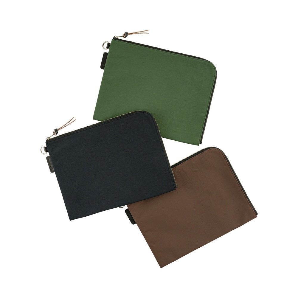 Three zippered A6 pouches in olive green, black, and brown, arranged diagonally on a solid white background.