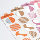 Three planner sticker sheets labeled January, February, and March, featuring geometric cutout stickers in orange, pink, brown, and metallic silver on a white background.