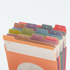 A set of colorful paper file folders arranged in a fan shape on a white background. The tabs are numbered 1 through 12 and come in multiple pastel and bright colors including orange, pink, purple, blue, green, and red.