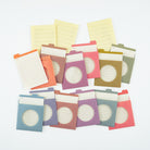 A set of colorful paper divider tabs and notepads arranged on a white background. The set includes various pastel and muted tones such as blue, purple, pink, orange, yellow, and green, with some featuring lined pages and others showing circular cutouts.
