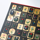Close up of sheet of Yoshie Watanabe stickers with gold foiling and colorful flower motifs on white background