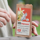 Hand holding SallyeAnder Hogwash stain removing soap in packaging on fence outside