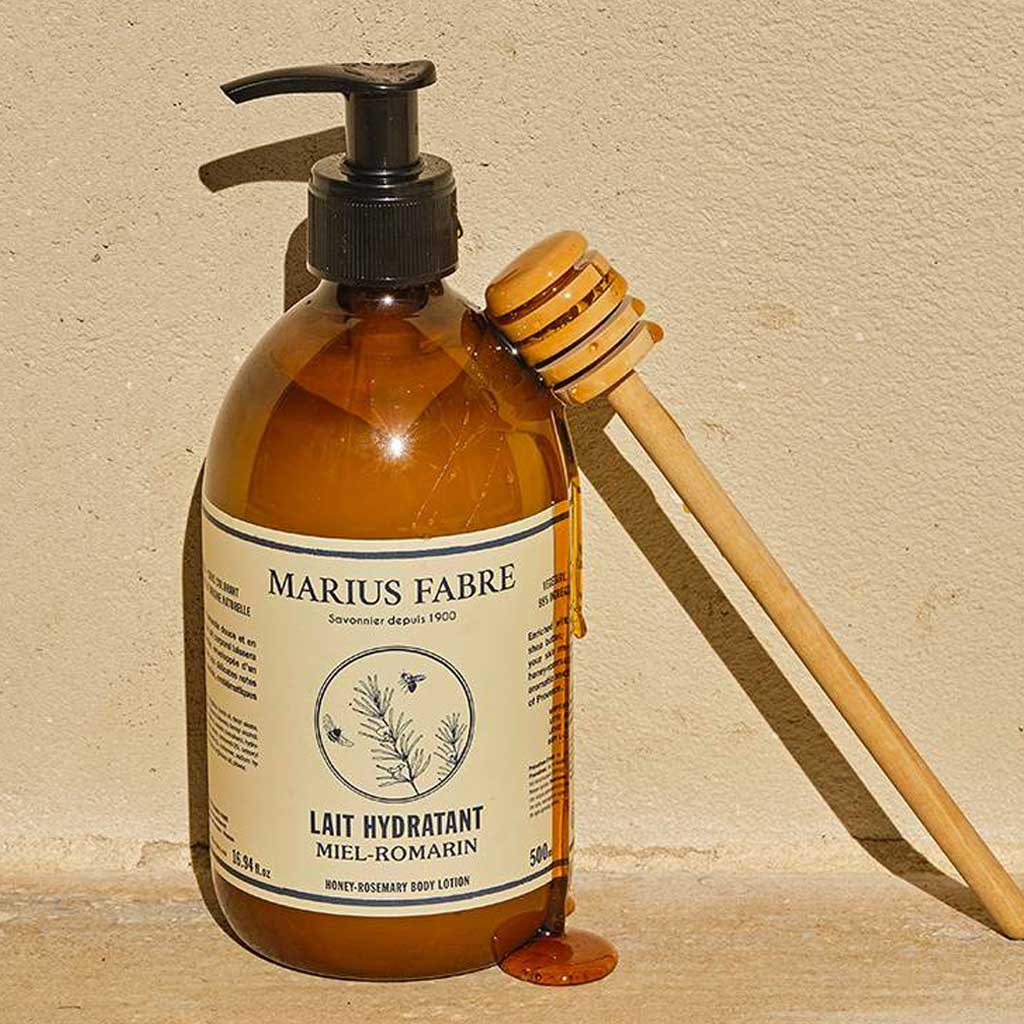 Marius Fabre body lotion pump bottle with a honey dipper on a beige background