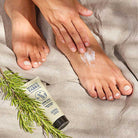 Person applying Marius Fabre honey and rosemary foot cream lotion on linen background
