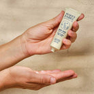 Hand applying a tube of Marius Fabre hand cream against a beige background
