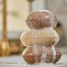 Stack of brown soap bars with bubbles on a white surface