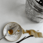 Vanilla extract with a spoon and vanilla bean on a white surface