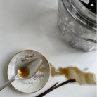 Vanilla extract with a spoon and vanilla bean on a white surface