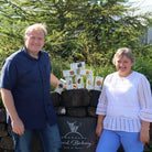 Couple standing outside next to stack of Island Bakery boxed goods on stone wall.