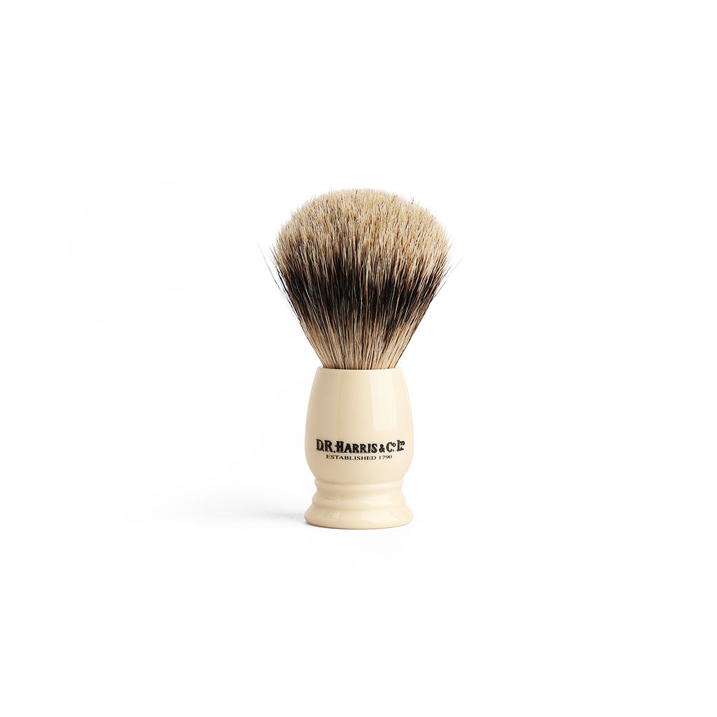 Shaving brush with imitation ivory handle and badger hair on a white background