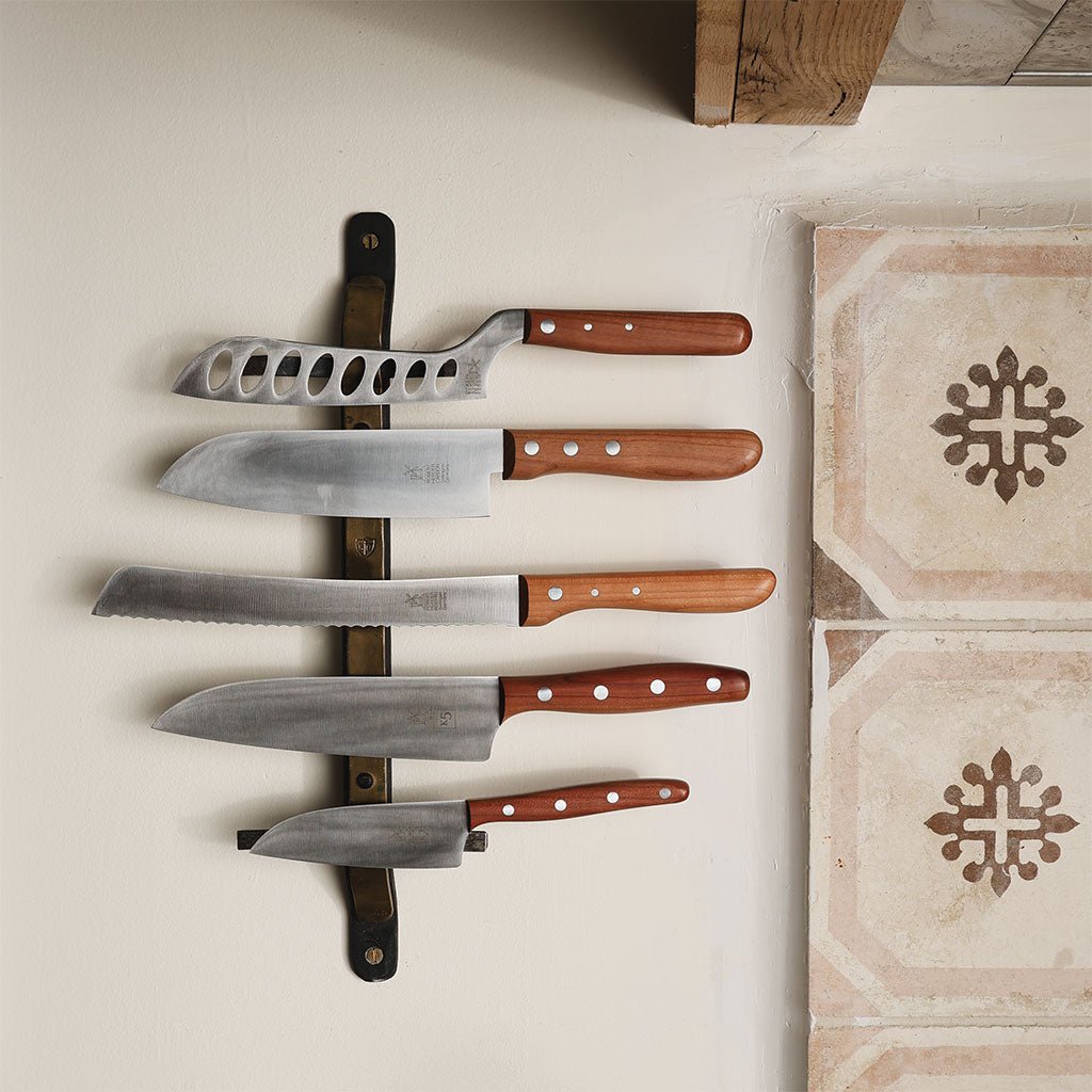 Wood-handled kitchen knives on a magnetic wall rack.