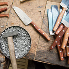 K2 utility knives with wooden handles on a wooden surface with nails and a hammer.