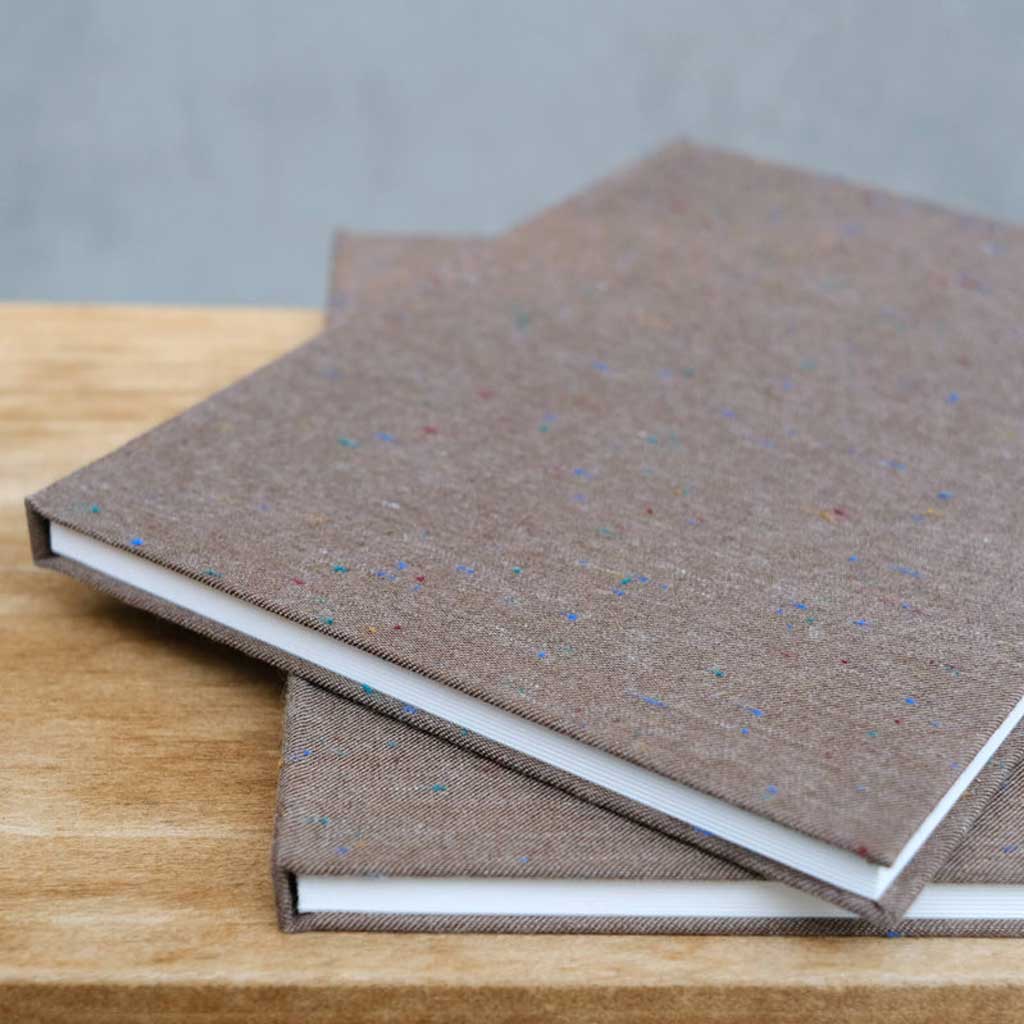 Two brown textured books stacked on a wooden surface with a gray background