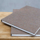 Two brown textured books stacked on a wooden surface with a gray background