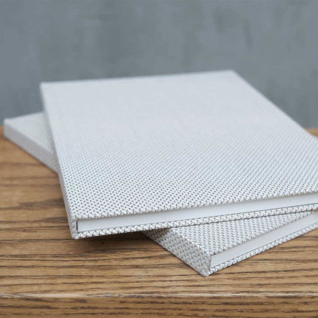 White woven notebook on a wooden surface with a gray background